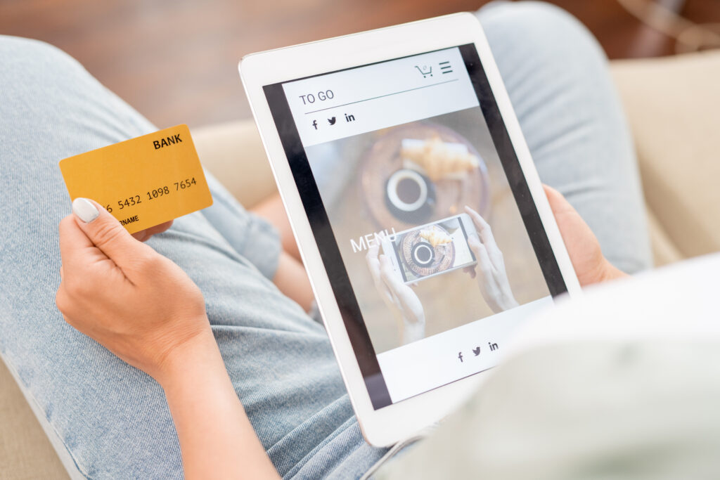 Vrouw winkelt online via tablet met creditcard in hand